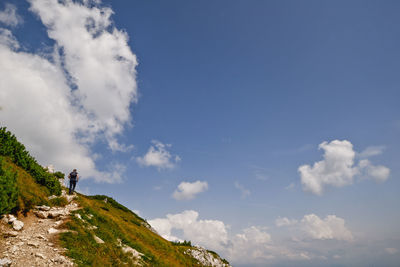 Low angle view of man standing against blue sky