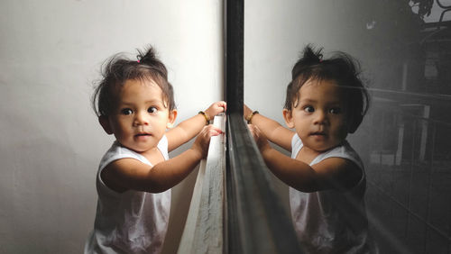 Portrait of young woman standing against wall