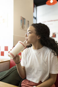 Woman drinking smoothie while sitting in cafe