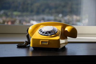 Close-up of yellow telephone on table