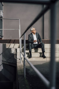 Senior businessman sitting on concrete stairs