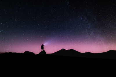 Silhouette person standing on field against sky at night