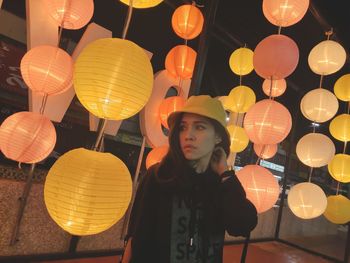 Portrait of woman with illuminated lanterns hanging at night