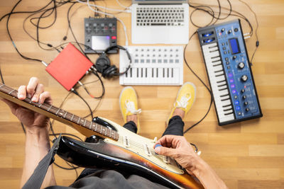 Low section of man playing guitar while standing on floor