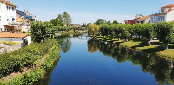 Canal amidst trees and buildings against sky