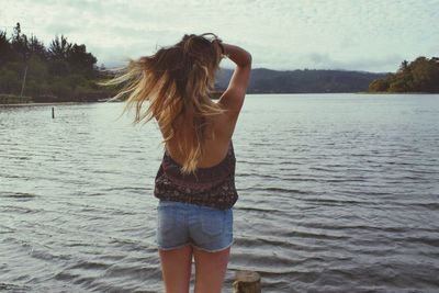 Rear view of woman standing by lake