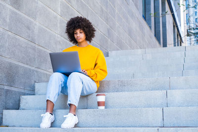 Full length of young woman sitting on staircase