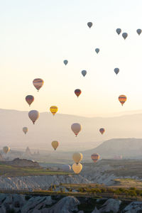 Hot air balloons flying over rocks against sky