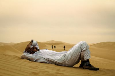 Men lying on arid landscape