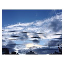 Low angle view of power lines against cloudy sky