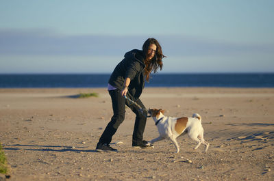 Full length of woman with dog at beach