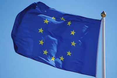 Low angle view of flag against clear blue sky