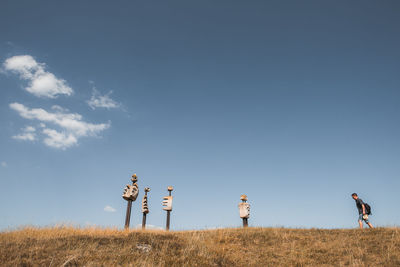 Rear view of people walking on field against sky