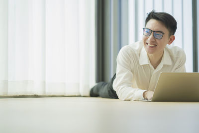 Portrait of smiling young man using laptop