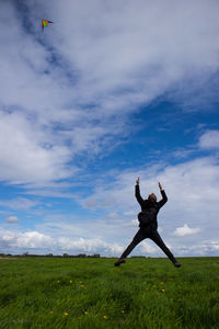 Low angle view of man flying kite on grassy field