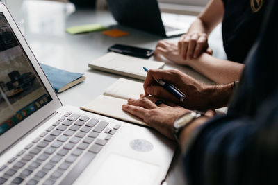 Midsection of man using laptop on table