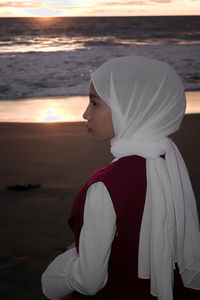 Side view of woman standing on beach during sunset