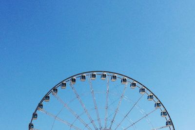 Low angle view of ferris wheel against clear blue sky