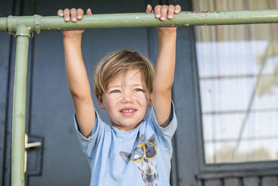 Close-up of boy holding railing outside house