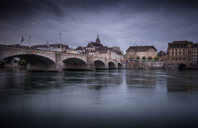 Arch bridge over river against sky in city at night