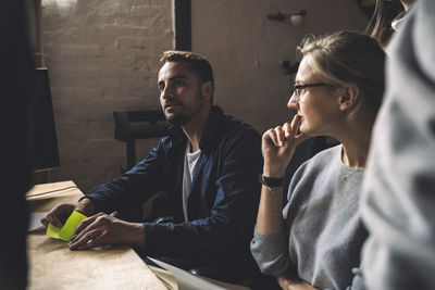 Male freelancer with colleagues sitting at workplace