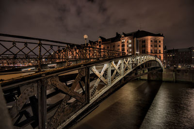 Illuminated bridge over river against sky in city