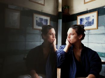 Young woman looking away while sitting in corridor