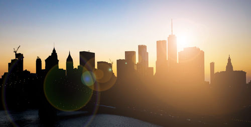 Modern buildings in city against sky during sunset