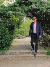 Full length portrait of young man standing against trees