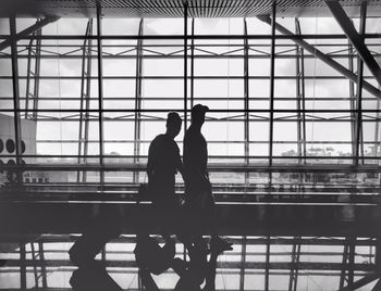 Silhouette people standing by railing