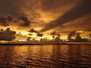 Scenic view of sea against dramatic sky during sunset