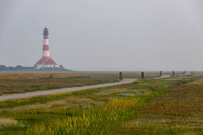 Lighthouse on field against sky