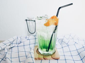 Close-up of orange soda on table against white wall