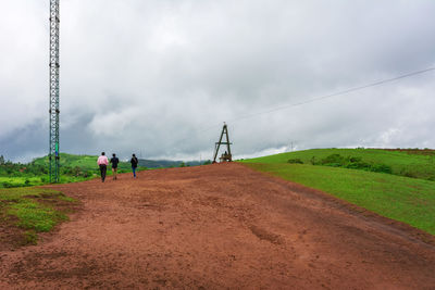 People walking on field against sky