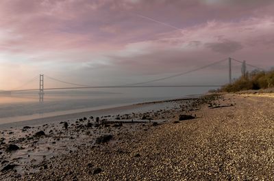 Suspension bridge over sea against sky during sunset