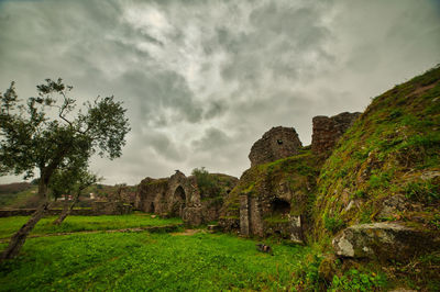 View of old ruin on field against cloudy sky