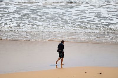 Rear view of man walking on beach