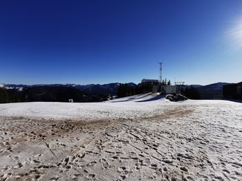 Snow covered land against clear blue sky