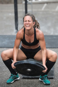 High angle view of mid adult woman lifting weights while crouching outdoors