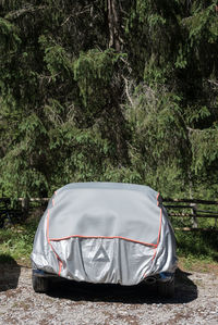 The gray and silver sun protection car cover. car parked in the forest parking covered with a cover