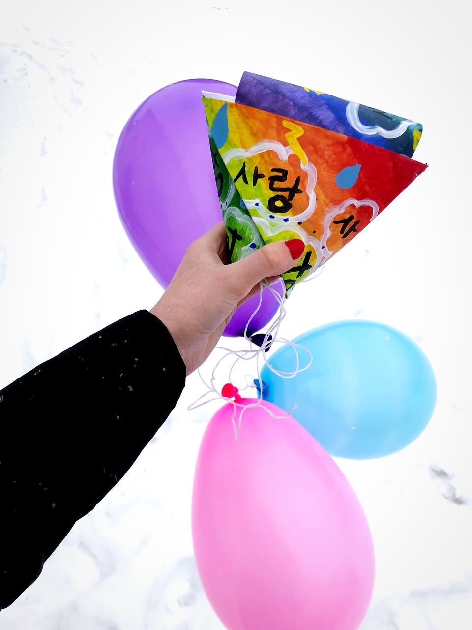CROPPED IMAGE OF HAND HOLDING BALLOONS