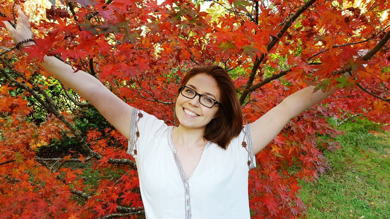 young adult, young women, tree, lifestyles, person, leisure activity, casual clothing, flower, standing, long hair, red, front view, looking at camera, growth, portrait, park - man made space, smiling