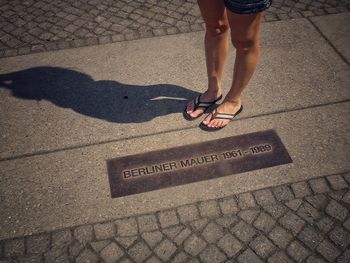 Low section of woman standing on cobblestone