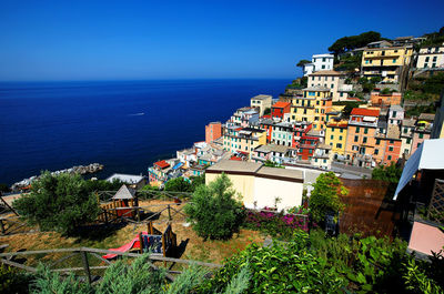 Buildings at manarola sea against clear blue sky