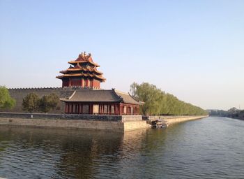 View of building by lake against clear sky