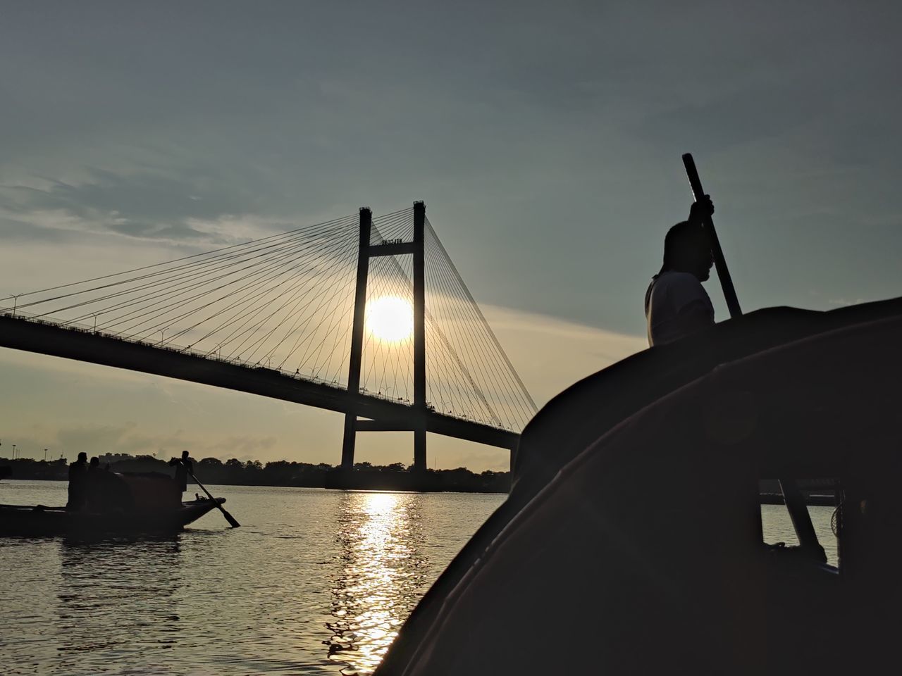 transportation, water, bridge, sky, architecture, built structure, suspension bridge, nature, reflection, travel destinations, evening, dusk, mode of transportation, sunset, travel, silhouette, nautical vessel, cloud, sea, engineering, tourism, horizon, city, sunlight, outdoors, boat, beauty in nature, vehicle, light, building exterior, scenics - nature