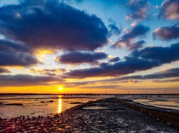 Scenic view of sea against dramatic sky during sunset