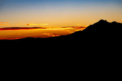 Scenic view of silhouette mountains against orange sky