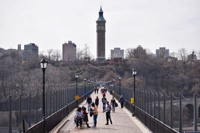 People at high bridge with water tower against sky