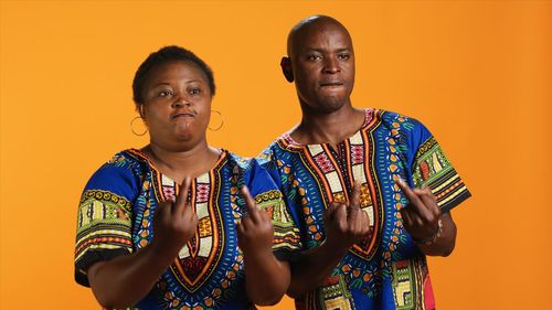 Portrait of smiling friends standing against yellow wall
